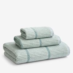 three towels stacked on top of each other in green and white striped pattern, with one folded