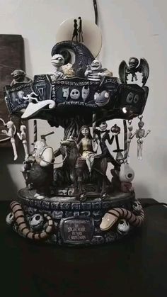 a black and white clock on top of a table next to a shelf filled with figurines