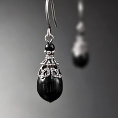 To make these earrings I dressed shiny black Austrian crystal pearls with Victorian style antiqued silver filigree and adornments.  --------------------------------------------------------------------------------------------- Dimensions and details:  - From the top of the hook ear wires to the bottom of the earrings, they measure approximately 1 and 5/16 in (33 mm) - Metal adornments are USA- and European-made antiqued silver-plated brass and antiqued silver-plated pewter, lead-free and nickel-f Black Antique Earrings, Black Ornate Dangle Jewelry, Gothic Black Drop Earrings, Victorian Black Dangle Earrings, Black Antique Drop Earrings, Pearl Teardrop Earrings, Victorian Style Jewelry, Hand Crafted Gifts, Wedding Jewelry Earrings