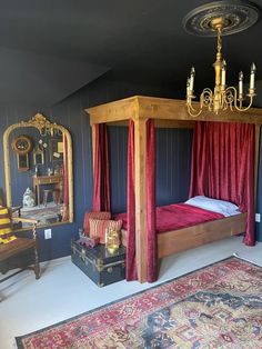 a canopy bed with red curtains in a bedroom next to a chair and rug on the floor