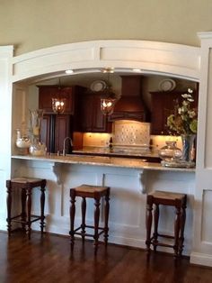 a kitchen with wooden flooring and white trim on the walls, along with two bar stools