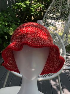 a white mannequin head wearing a red knitted hat on a wooden deck