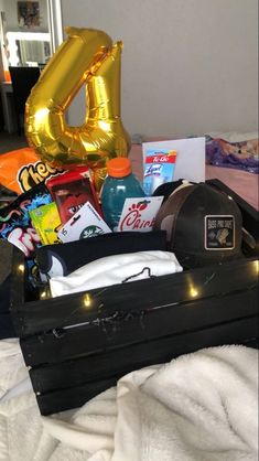 an open suitcase filled with items on top of a white bed next to a gold balloon