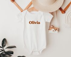 Looking for a special gift? Our personalised baby onesie® is the ideal choice! Customise this onesie® with your own text and make it the most memorable gift for a new mama, baby announcement, or family photo tee! The perfect gift for a newborn or any special little one in your life, our personalised onesie® is printed with eco-friendly inks on 100% cotton, for the softest feel. The Details: * Super soft and comfy!  * Lightweight and breathable * 100% cotton for the softest feel imaginable * The Customizable White Onesie As A Gift, Family Matching White Onesie With Name Print, Customizable White Onesie As Gift, Casual Personalized White Onesie, Casual White Personalized Onesie, Custom Name White Cotton Onesie, Personalized White Bodysuit For Gift, White Onesie With Name Print For Gift, Casual Letter Print Onesie As Gift