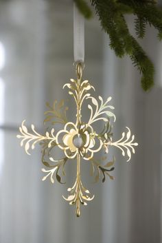 a gold snowflake ornament hanging from a christmas tree