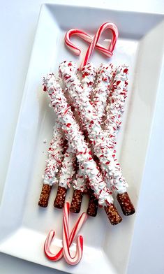 some candy canes are on a white plate with red and white icing in the shape of letters