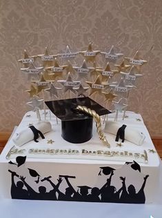 a graduation cake decorated with gold stars and black mortare on top, surrounded by confetti