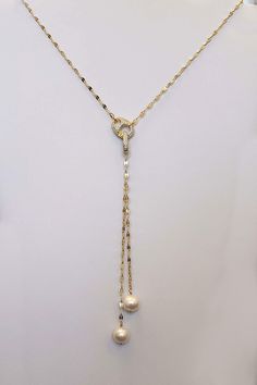 Our Pearl Lariat Necklace is a stunning piece of jewelry designed to make a bold statement. This necklace features 2 freshwater pearls handwrapped onto a gold sequin chain. crafted from high-quality materials, creating a luxurious and contemporary look. The lariat style adds a touch of elegance and versatility, allowing you to adjust the length and drape to suit your outfit and preference. The focal point of this necklace is our stunning carabiner pave clasp that adds a stunning contemporary fla Elegant White Gold Lariat Chain Necklace, Pearl Charm Lariat Jewelry, Elegant Lariat Chain Necklace With Lobster Clasp, Pearl Lariat Necklace With Chain, Elegant Gold Lariat Necklace With Lobster Clasp, Pearl White Long Necklace With Clavicle Chain, Pearl White Pearl Jewelry With Chain, Luxury Pearl Lariat Necklace, Luxury Lariat Necklace With Lobster Clasp