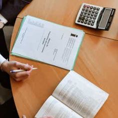 two people sitting at a table with papers and calculators on top of it