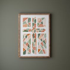 a cross made out of different colored tiles on a wall in a room with green walls