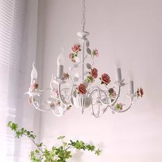 a white chandelier hanging from a ceiling in a room with flowers on it