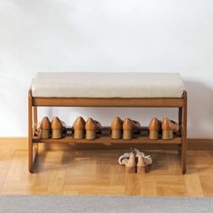 a wooden bench with several pairs of shoes on the floor next to it and a wall in the background