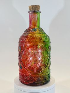 a colorful glass bottle sitting on top of a white stand