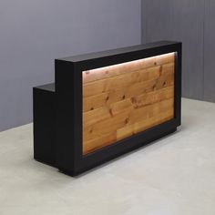 a black and wood reception table sitting on top of a white floor next to a gray wall