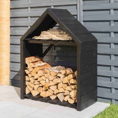 a pile of firewood sitting in front of a wooden structure on the side of a building