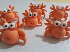 four orange crabs with googly eyes sitting on top of a white countertop next to each other