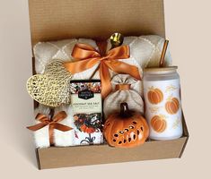 an open box with some items in it and a pumpkin on the side, sitting next to a mug