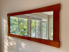 a large mirror hanging on the side of a wall next to a plant in a vase