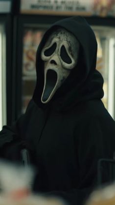 a person in a black hoodie with a scream mask on and mouth wide open