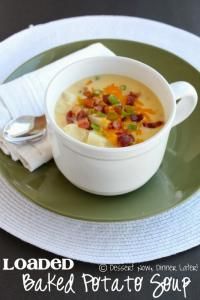 a bowl of loaded baked potato soup sits on a plate with a spoon and napkin