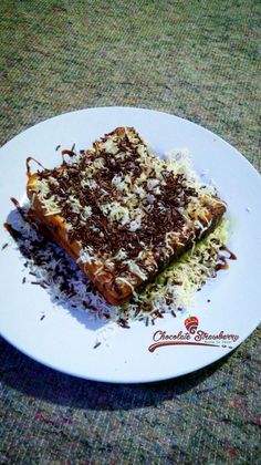 a white plate topped with a piece of cake covered in chocolate and sprinkles