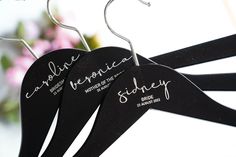 three black hangers with names on them and flowers in the backgroung