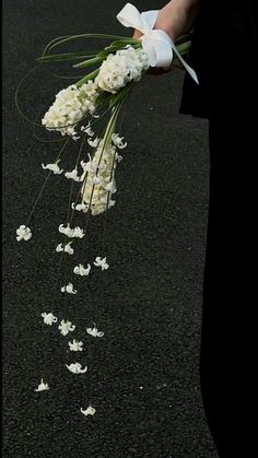 a bouquet of white flowers is being carried down the street