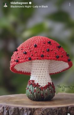 a red and white crocheted mushroom sitting on top of a tree stump