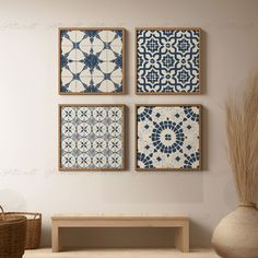 three blue and white tiles are hanging on the wall above a wooden bench in front of a wicker basket