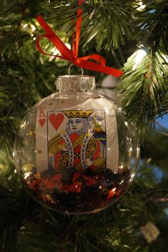 a glass ornament with a playing card on it hanging from a christmas tree