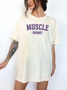 "💚 Welcome to G O L D E N D U S K A P P A R E L 💚 Make a style statement with our exclusive MUSCLE MOMMY tee on the Comfort Colors 1717 Adult Unisex Heavyweight T-shirt. Designed in a heritage fit with dropped shoulders and a boxy shape to give that desired vintage look and style of the garment. This garment-dyed, soft-washed tee provides a vintage aesthetic and a soft, welcoming feel for everyday comfort. DETAILS - 6.1 oz., Heavyweight - Fit: Relaxed (heritage fit: unstructured, straight, boxy shape) - Style: Unisex Adult (available in sizes S-XXL) - Sizing: Runs true to size. Refer to the Size Guide and Size Chart images. Note: Unisex adult sizing falls between men's and women's traditional sizing. So, a unisex large would be bigger than a woman's large but smaller than a man's large. Workout Cotton T-shirt With Screen Print, Basic Sports Tops With Screen Print, Basic Sports Top With Screen Print, Basic Graphic Gym T-shirt, Sporty Oversized Tops With Letter Print, Cotton Muscle Tee In Athleisure Style, Basic Gym Tops With Letter Print, Oversized Sports Tops With Logo Print, Basic Gym Top With Letter Print