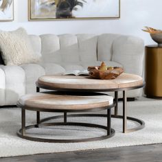 a living room with white couches and two tables in front of the sectional sofa