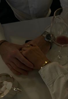 two people holding hands at a table with wine glasses