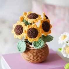 crocheted sunflowers in a basket on a table next to a flower pot