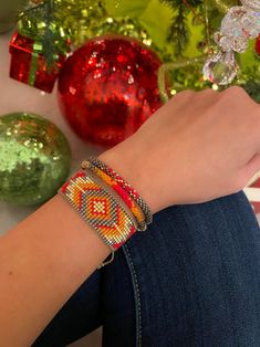 a woman's hand wearing a beaded bracelet next to christmas ornaments and baubles