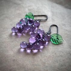 lilac grape earrings inspired by the fruit jewellery of the 1930's-1950's. lavender lilac grapes with emerald green leaves.  All parts are hand shaped  from molten glass and annealed in a digitally controlled kiln for extra durability. This colour shifts in different lighting.  a lavender-lilac in natural sunlight and pale blue in artificial light. They measure approx 1 7/8inch long, including the hooks, which are made of oxidised sterling silver.   *These earrings are made to order, so may diff Fruit Jewellery, Glass Grapes, Grape Earrings, Fruit Jewelry, Artificial Light, Fruit Earrings, Earrings Inspiration, Natural Sunlight, Hand Shapes