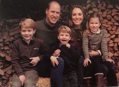 a family posing for a photo in front of firewood