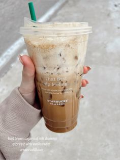 a woman holding up a cup of iced coffee