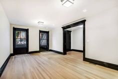 an empty room with wooden floors and black doors