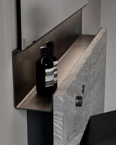 a black bottle sitting on top of a counter next to a metal shelf and mirror