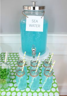 a table topped with mason jars filled with blue liquid and drinking glasses on top of it