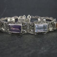 This gorgeous vintage bracelet is sterling silver with 6x10mm emerald cut gemstones and marcasites. It features 3 amethysts, 3 blue topaz and 2 citrines. Measurements: 1/2 of an inch wide - 6 1/2 wearable inches Weight: 24.9 grams Marks: 925, CL Condition: Excellent Vintage Sterling Silver Bracelet With Gemstone, Silver Gemstones With Jewels In Fine Jewelry Style, Classic Silver Bracelet With Jewels, Elegant Silver Gemstones With Jewels, Vintage Silver Gemstone Bracelets, Antique Silver Gemstone Bracelet, Vintage Silver Amethyst Bracelets, Vintage Silver Bracelets With Gemstones, Art Deco Silver Amethyst Jewelry