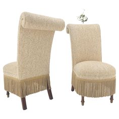 a pair of beige chairs with fringe trim