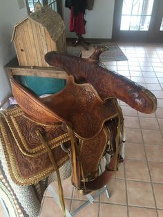 an old saddle sitting on top of a chair in a room with tile flooring