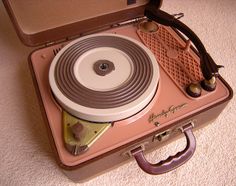 a pink suitcase sitting on top of a carpeted floor next to a pair of scissors