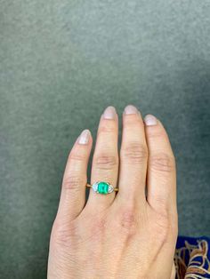 a woman's hand with an emerald ring on it