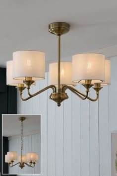 a chandelier with white shades hanging from the ceiling