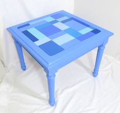 a blue table with squares painted on the top and bottom in shades of light blue