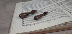 two wooden spoons resting on top of an open book with music sheets in the background