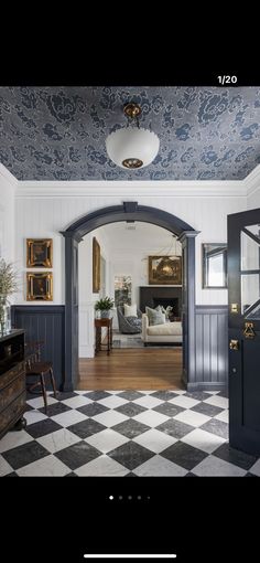 an open door leading to a living room with black and white checkered flooring